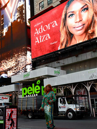 Adora Aiza in front of her first featured New York City Billboard. Adora says that it is her 5 year old dream come true as she watches with her pjs before heading to a flight for a show out in Europe. Adora Aiza in front of her first featured New York City Billboard. Adora says that it is her 5 year old dream come true as she watches with her pjs before heading to a flight for a show out in Europe.